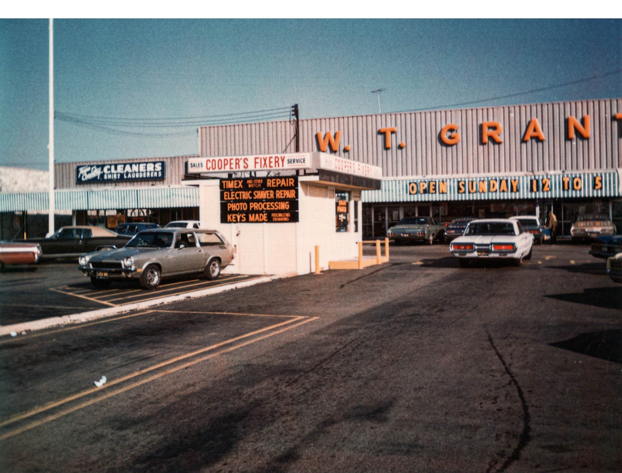A vintage style photo of the "Cooper's Fixery" watch service in a parkinglot. 